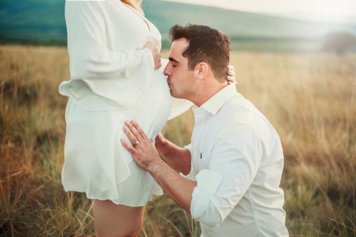 man-kissing-belly-of-pregnant-woman-in-green-field-2168822-1024x683